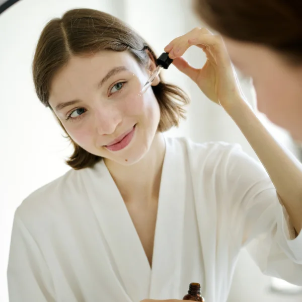Skincare model holding a serum dropper beside her face
